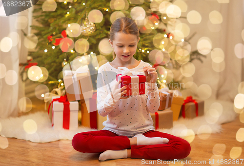 Image of smiling girl with christmas gift at home