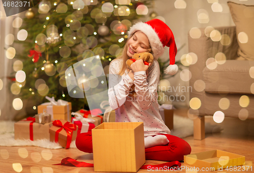 Image of smiling girl in santa hat with christmas gift