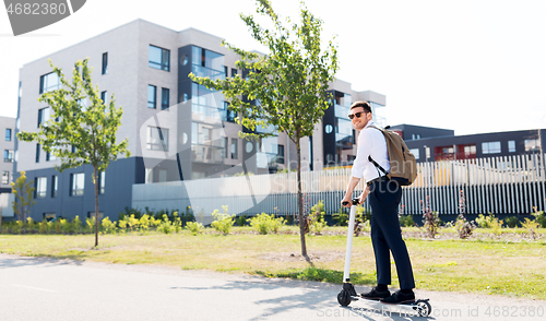 Image of businessman with backpack riding electric scooter