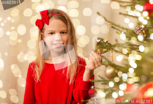 Image of happy girl in red decorating christmas tree