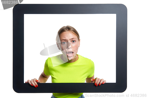 Image of Indignant girl peeking through digital tablet frame