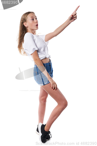 Image of Full length of surprised teen girl pointing to side at blank copy space