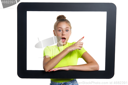 Image of Teen girl looking through digital tablet frame pointing finger to side