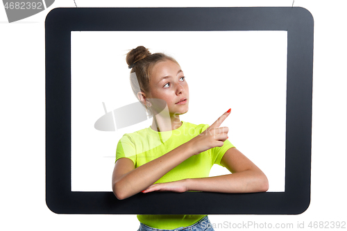 Image of Teen girl looking through digital tablet frame pointing finger to side