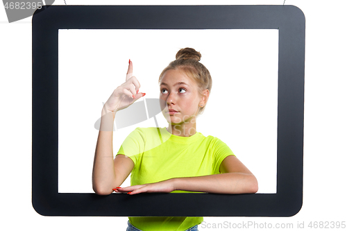 Image of Teen girl looking through digital tablet frame pointing finger up