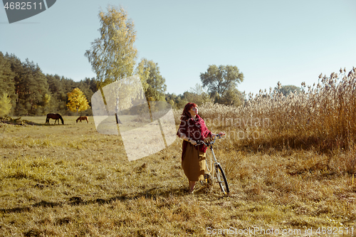 Image of Pretty girl riding bicycle in field