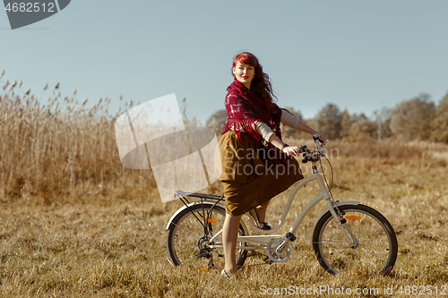 Image of Pretty girl riding bicycle in field