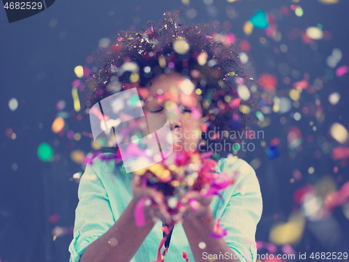 Image of black woman blowing confetti in the air