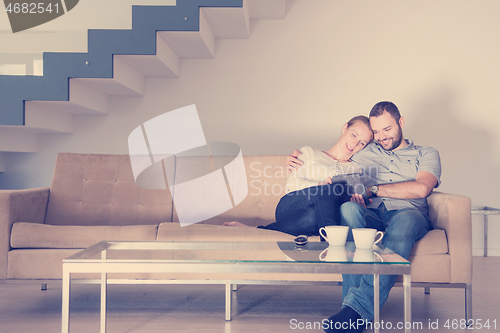 Image of romantic couple relaxing at  home with tablet computers