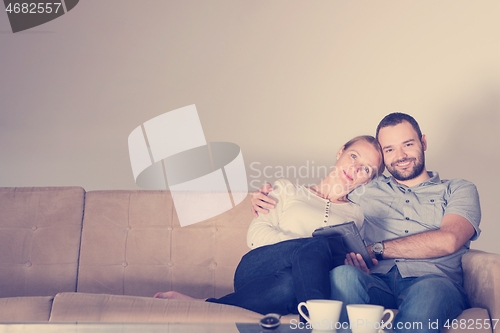 Image of romantic couple relaxing at  home with tablet computers