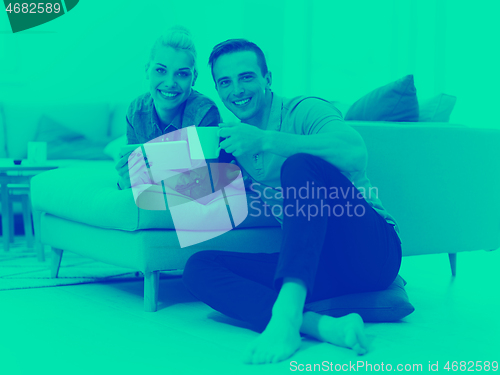 Image of couple relaxing at  home with tablet computers