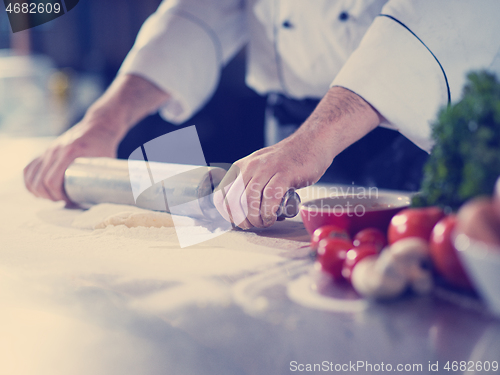 Image of chef preparing dough for pizza with rolling pin