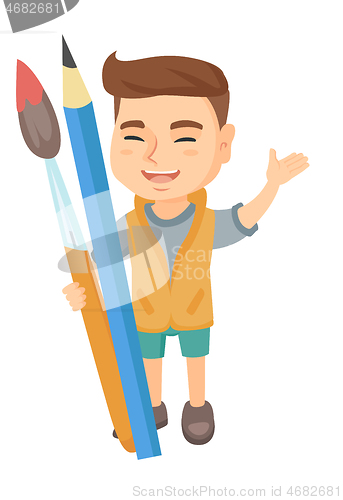 Image of Smiling boy holding big pencil and paintbrush.