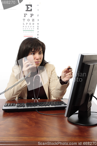 Image of Doctor using computer and telephone