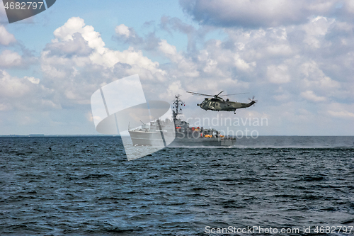 Image of NATO rescue mission in sea with ship and helicopter.