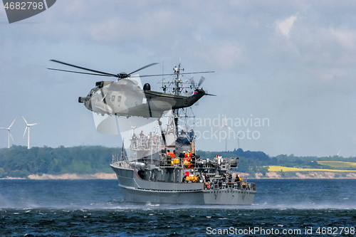 Image of NATO rescue mission in sea with ship and helicopter.