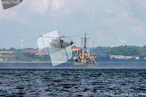 Image of NATO rescue mission in sea with ship and helicopter.