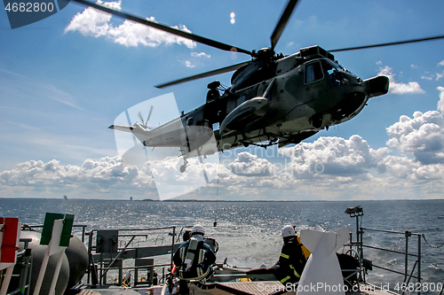 Image of NATO rescue mission in sea with ship and helicopter.