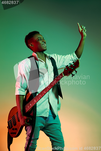 Image of African American handsome jazz musician holding bass guitar and welcomes the audience.