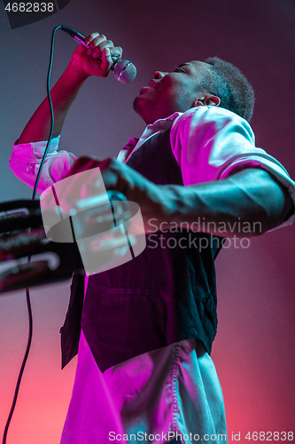 Image of African American handsome jazz musician playing tambourine and singing.