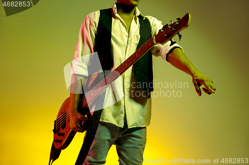 Image of African American handsome jazz musician holding bass guitar and welcomes the audience.