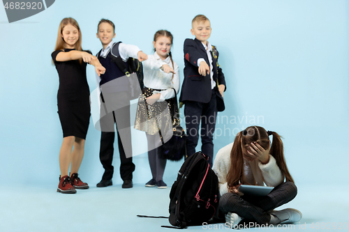 Image of Little girl sitting alone on floor and suffering an act of bullying.