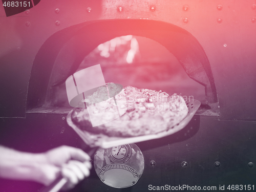 Image of chef removing hot pizza from stove