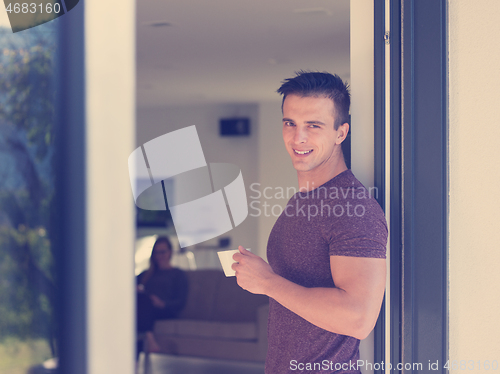 Image of man drinking coffee in front of her luxury home villa