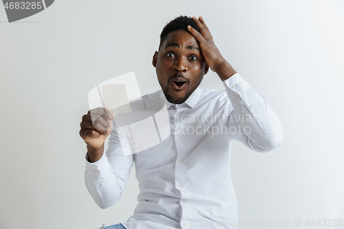 Image of Young afro man with a surprised happy expression won a bet on gray studio background. Human facial emotions and betting concept.