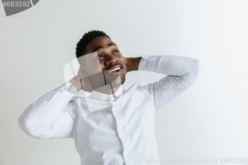 Image of Close up portrait of a happy young african american man laughing against gray background.