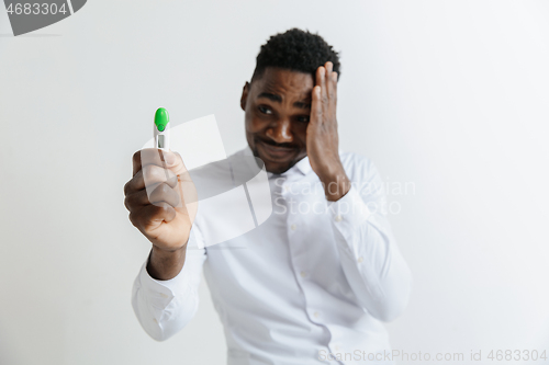 Image of Young unhappy african american man looking at pregnancy test. Handsome sad man frustrated and having problems. Guy depressed because of result of pregnancy test