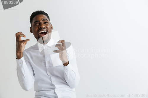 Image of Wow. Attractive male half-length front portrait on grey studio backgroud. Young afro emotional surprised bearded man standing with open mouth. Human emotions, facial expression concept.