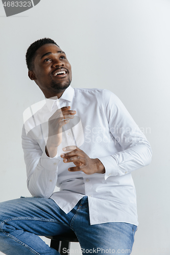 Image of Close up portrait of a happy young african american man laughing against gray background.