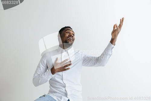 Image of Grateful happy pleased african man holding hands on chest.