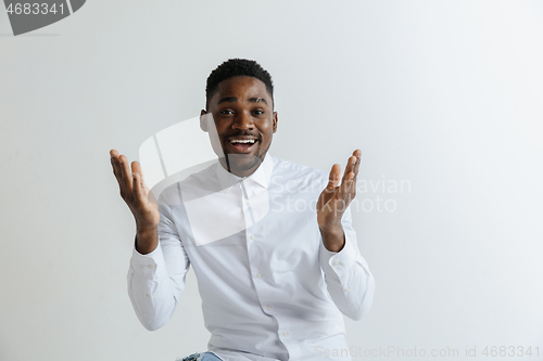 Image of Wow. Attractive male half-length front portrait on grey studio backgroud. Young afro emotional surprised bearded man standing with open mouth. Human emotions, facial expression concept.