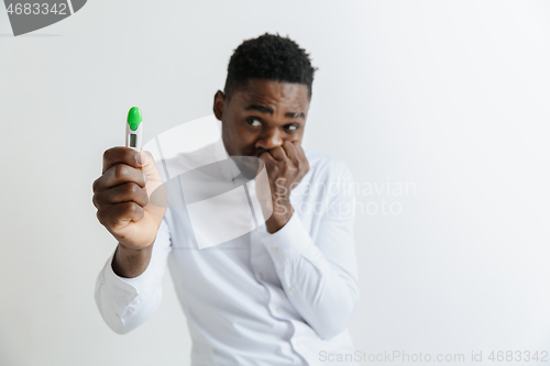 Image of Young unhappy african american man looking at pregnancy test. Handsome sad man frustrated and having problems. Guy depressed because of result of pregnancy test