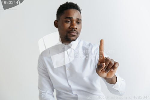 Image of Young african american guy interacts with empty space. Negative space to insert your text or image.