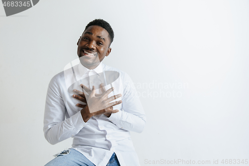 Image of Grateful happy pleased african man holding hands on chest.