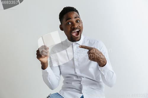 Image of Young afro man with a surprised happy expression won a bet on gray studio background. Human facial emotions and betting concept.