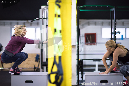 Image of athletes working out  jumping on fit box