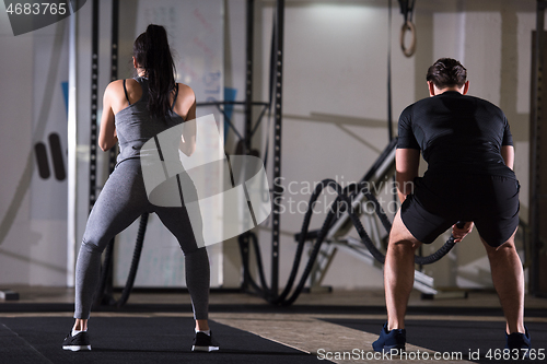 Image of sports couple doing battle ropes cross fitness exercise