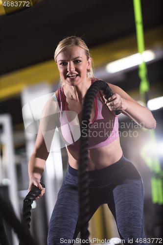 Image of athlete woman doing battle ropes cross fitness exercise