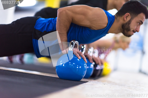 Image of young athletes doing pushups with kettlebells