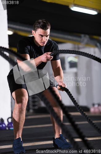 Image of athlete man doing battle ropes cross fitness exercise