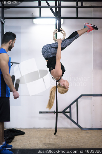 Image of woman working out with personal trainer on gymnastic rings