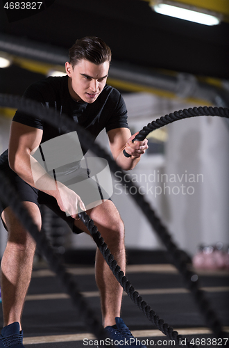 Image of athlete man doing battle ropes cross fitness exercise