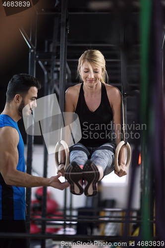 Image of woman working out with personal trainer on gymnastic rings