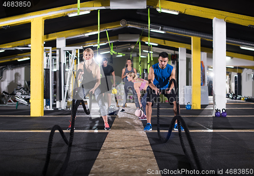 Image of sports couple doing battle ropes cross fitness exercise