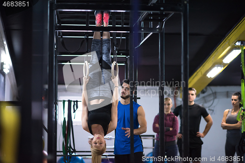 Image of woman working out with personal trainer on gymnastic rings