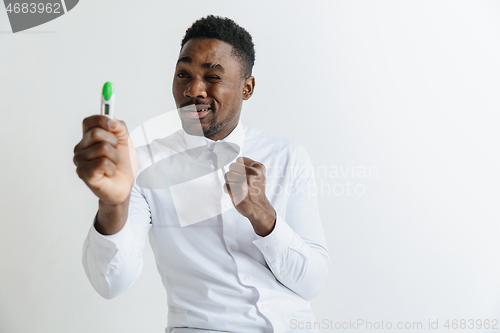 Image of Young unhappy african american man looking at pregnancy test. Handsome sad man frustrated and having problems. Guy depressed because of result of pregnancy test